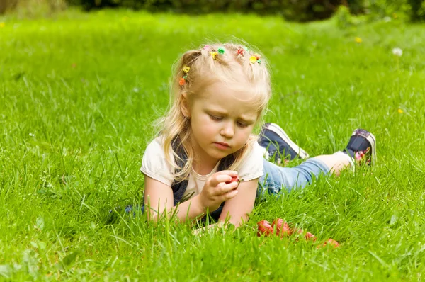 Lilla flickan äta en jordgubbe i naturen — Stockfoto