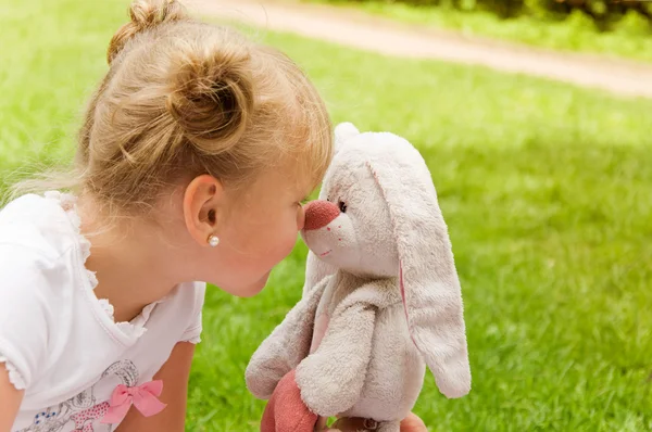 Маленькая девочка играет со своей любимой мягкой игрушкой — стоковое фото