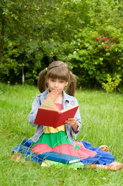 Lilla flickan läsa en bok som är intressant — Stockfoto