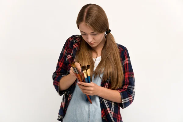 Mooie jonge kunstenaar holding een palet en penselen. — Stockfoto