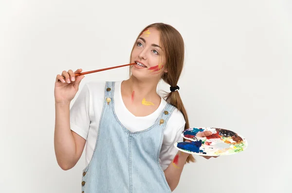 Pretty young artist holding a palette and brushes. — Stock Photo, Image
