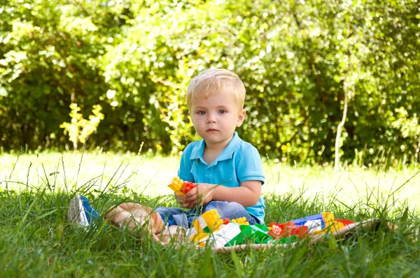 Liten pojke leker med en konstruktor i naturen. — Stockfoto