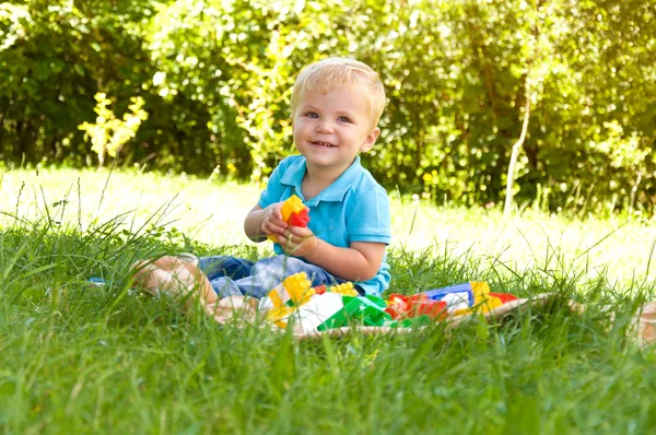 Niño juega con un constructor en la naturaleza — Foto de Stock