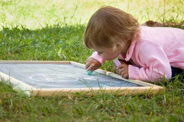 Маленькая девочка рисует мелом на доске — стоковое фото