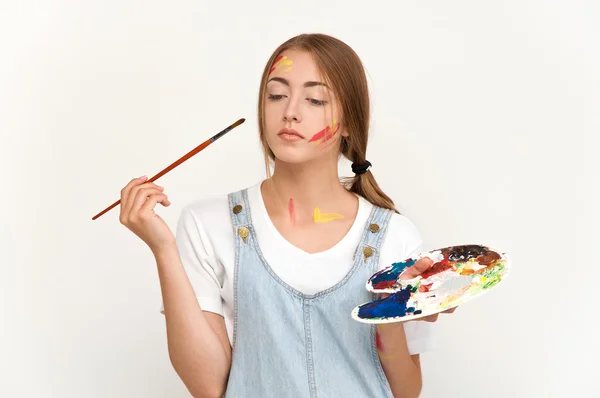 Pretty young artist holding a palette and brushes — Stock Photo, Image