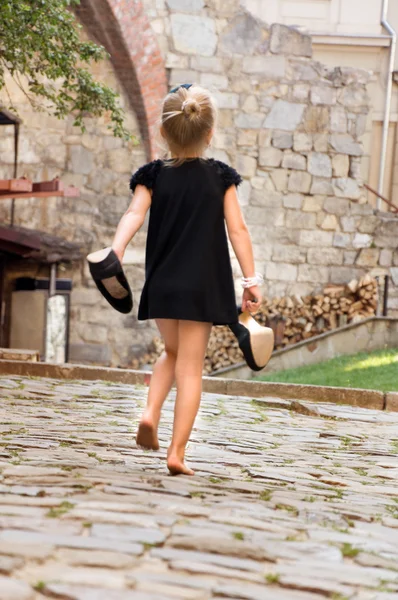 Menina segurando seus sapatos e foge descalço — Fotografia de Stock