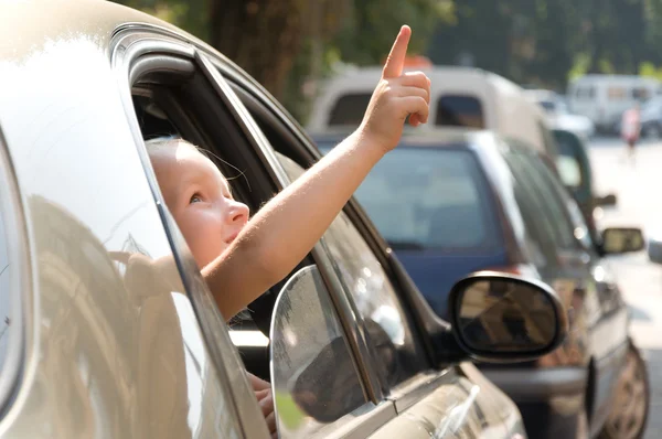 Kleine meisje kijkt uit het raam in de auto — Stockfoto