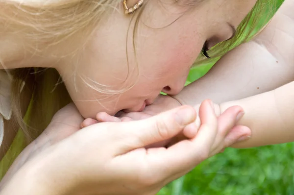Maminka polibky rukou její malá dcera — Stock fotografie