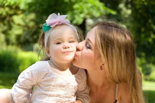 Madre besando a su hija en la mejilla — Foto de Stock