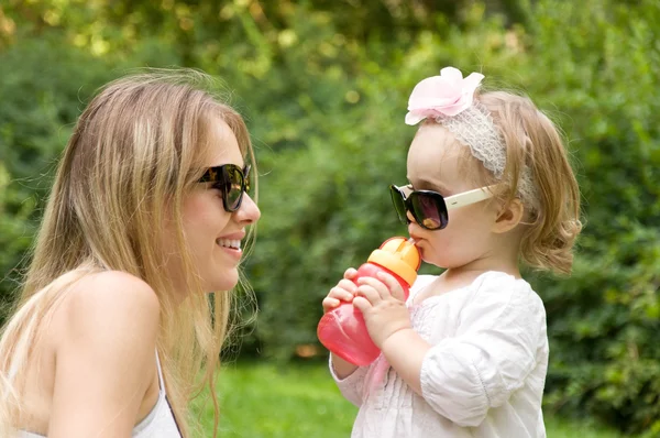 Niña en gafas de sol de pie delante de su madre — Foto de Stock