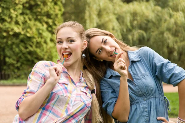 Duas meninas namoradas comer pirulito — Fotografia de Stock