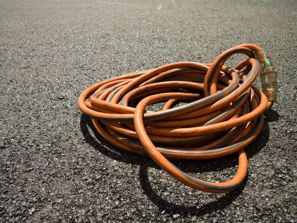 El cable de extensión naranja en tierra en el sitio de construcción —  Fotos de Stock