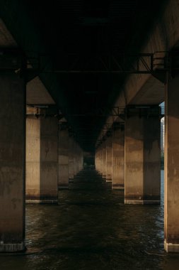 Denizde destek kirişleri olan köprünün altındaki nehrin kasvetli ve karanlık manzarası..