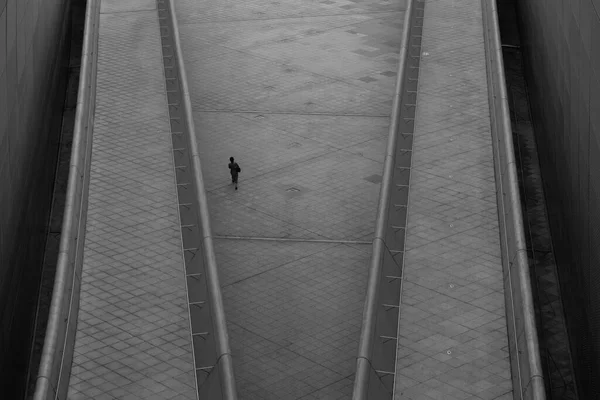 Overhead view of business woman walking alone in futuristic looking area in a city.