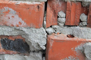 Kırık kahverengi tuğlalar, siyah noktalar ve gri beton.