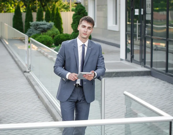 Bonito homem de negócios em terno de pé perto de prédio de escritórios — Fotografia de Stock