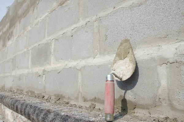 Trowel di cinderblock latar belakang abu-abu. dengan latar belakang batu bata adalah trowel . — Stok Foto