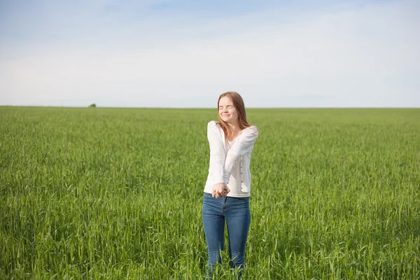 Mulher de braços abertos no campo de trigo verde pela manhã — Fotografia de Stock