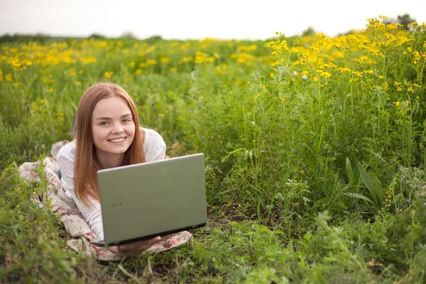 Young smiling woman with notebook in park looking at notebook computer