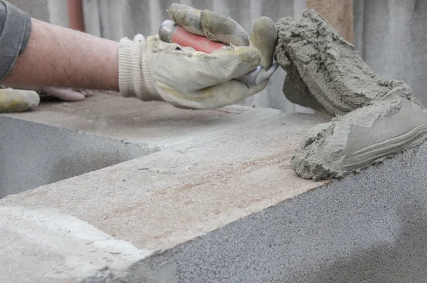 Worker aligns with a spatula, lay brick cinderblocks Stock Photo