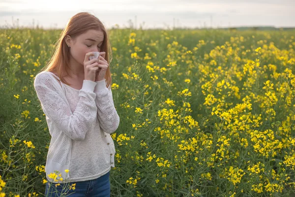 Pollen allergi, pige nysen i et felt af blomster - Stock-foto