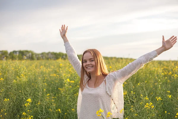 Frau mit offenen Armen im grünen Rapsfeld am Morgen — Stockfoto