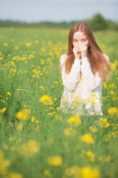 Pollenallergie, Mädchen niesen in einem Blumenfeld. — Stockfoto
