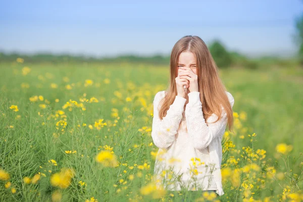 Аллергия на пыльцу, девушка чихает на поле цветов . — стоковое фото