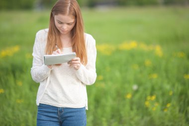 Defter ve kalem çim üzerinde mutlu kız Avrupa görünüm duran