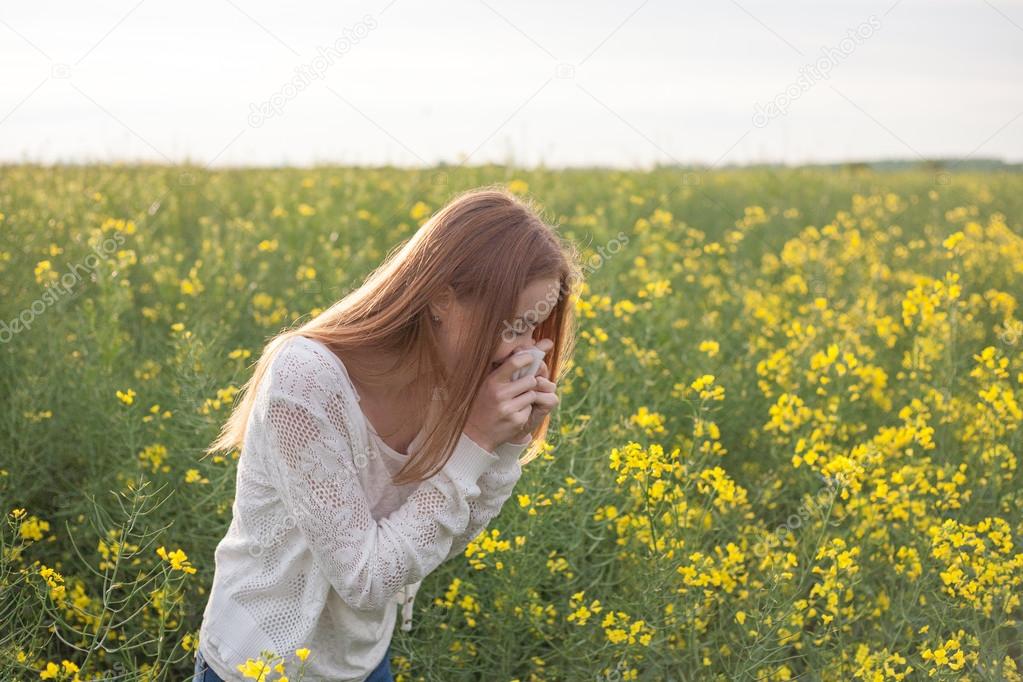 女の子の花の菜の花のフィールドでくしゃみ花粉症 ストック写真 C Valeriikalantai