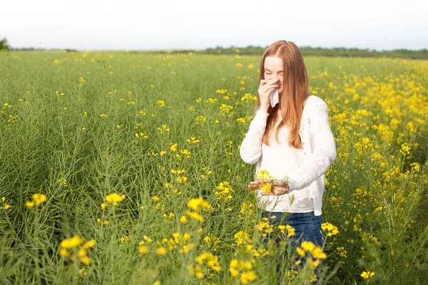 Alergia al polen, niña estornudando en un campo de colza de flores —  Fotos de Stock