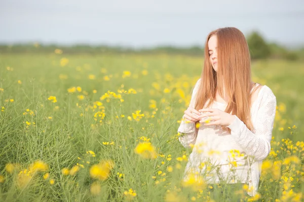 Alergia al polen, niña estornudando en un campo de colza de flores —  Fotos de Stock