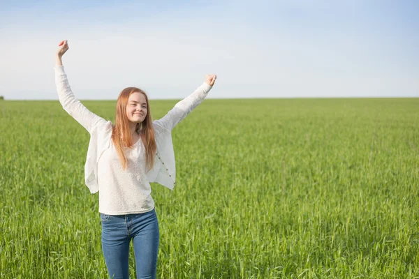 Vrouw met open armen op het gebied van de groene tarwe op de ochtend — Stockfoto