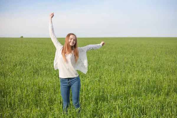 Vrouw met open armen op het gebied van de groene tarwe op de ochtend — Stockfoto