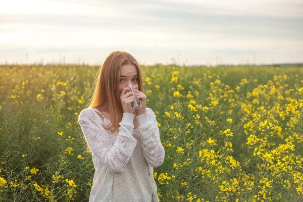 Alergia al polen, niña estornudando en un campo de colza de flores —  Fotos de Stock