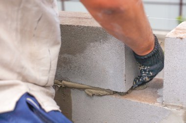 Oluşturucu bir kül blok bina inşası için koyar. usta eller bir brickwall koyar. Tuğlalar.