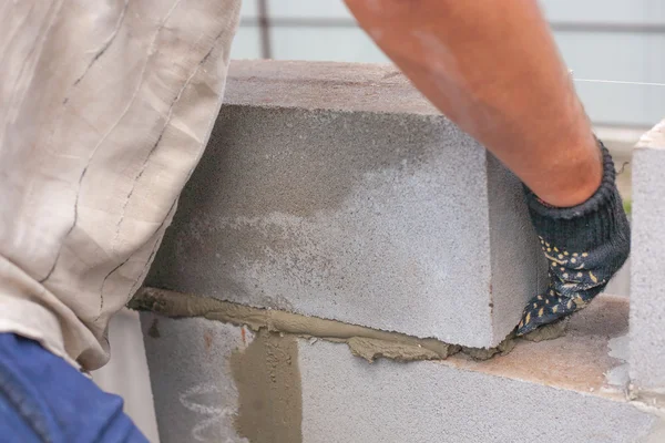 Oluşturucu bir kül blok bina inşası için koyar. usta eller bir brickwall koyar. Tuğlalar.
