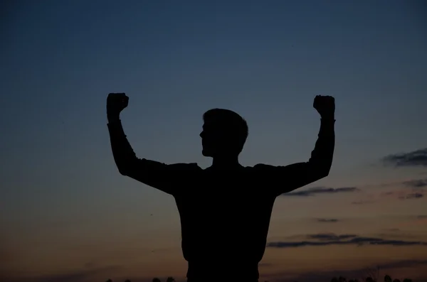 Silhouette of a strong fighter. Confident young fitness man with strong hands and clenched fists. Dramatic light — Stock Photo, Image