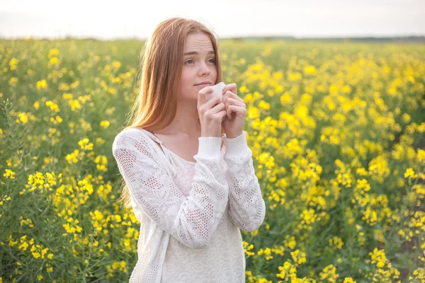 Allergie au pollen, fille éternuant dans un champ de fleurs de colza . — Photo