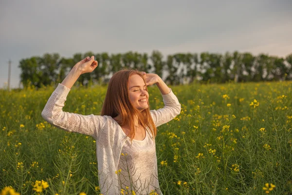 Mulher com os braços abertos no campo de colza verde pela manhã. — Fotografia de Stock