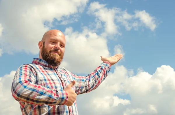 Homem sem pêlos feliz com barba apontando para céu lindo nublado . — Fotografia de Stock
