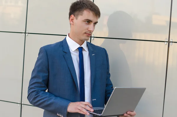 Empresário confiante e bem sucedido segurando um laptop . — Fotografia de Stock