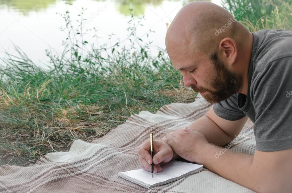 Man writing in his notebook in forest.