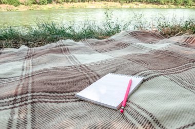 defter ile kalem ve alan yeşil otların arasında düz lay ile ilgili notlar.