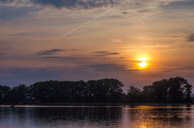 Göl üzerinde güzel parlak bulutlu gün batımı.