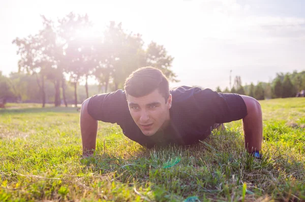 Primer plano de un hombre haciendo flexiones en la hierba con el horizonte en el fondo . — Foto de Stock