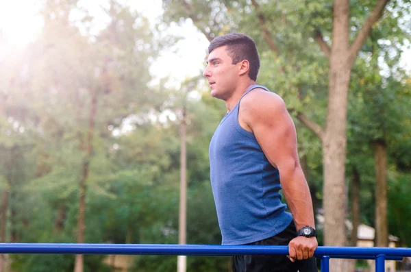 Fitness, deporte, ejercicio, entrenamiento y el concepto de estilo de vida - joven haciendo tríceps inmersión en barras paralelas al aire libre . — Foto de Stock