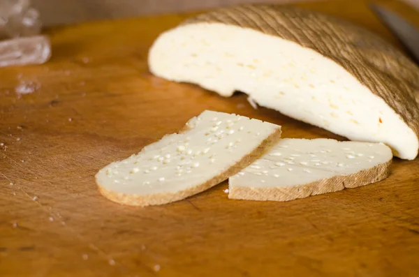 Сыр пармезан нарезанный на оливковой доске, над дубовым столом . — стоковое фото