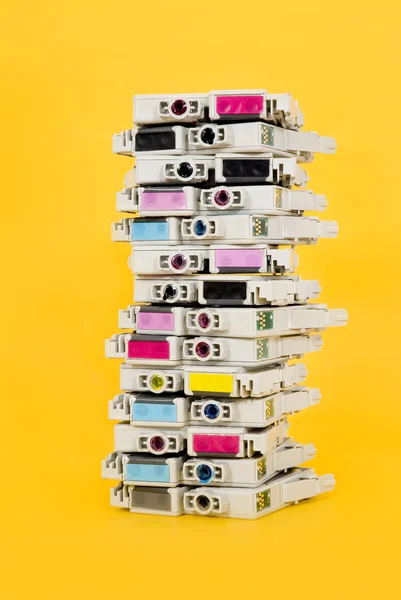 Cartuchos de tinta esgotados empilhados em fundo amarelo — Fotografia de Stock