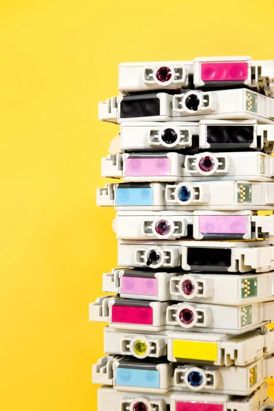 Ink cartridges exhausted stacked on yellow background — Stock Photo, Image